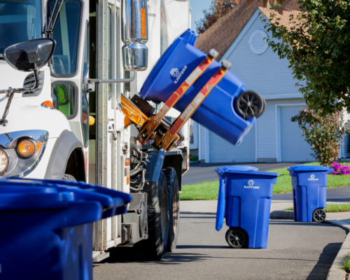 A recycling truck picking up recycling bins in a neighborhood